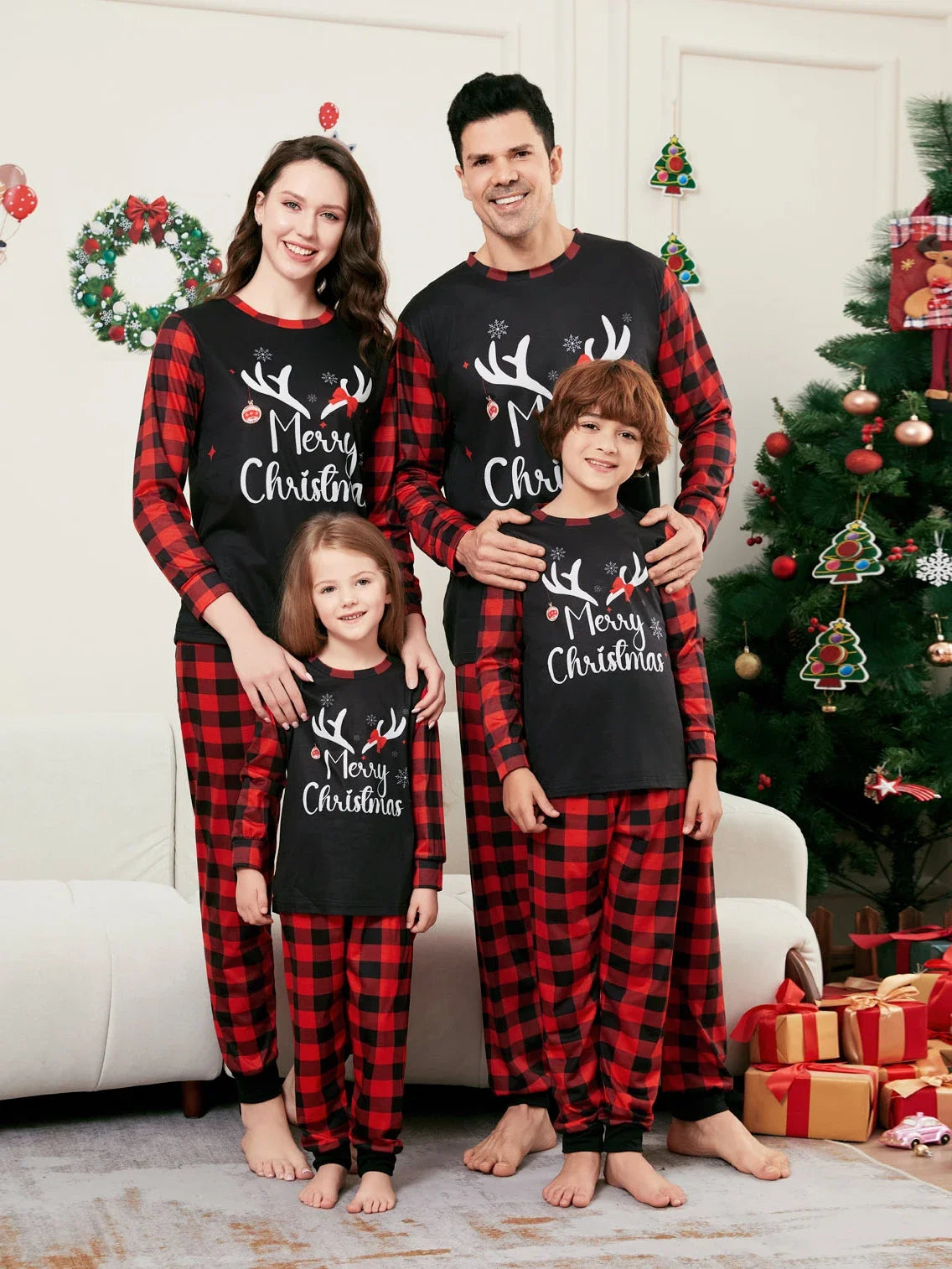 Famille en pyjamas de Noël noirs à inscription Merry Christmas, avec manches et pantalons à carreaux rouges et noirs.